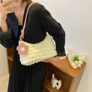 Détail du sac texturé à bulles blanc avec bandoulière rose et charm floral en gros plan