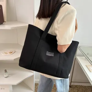 Minimalist black canvas tote bag with fashion tag, spacious shoulder shopping bag for women