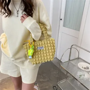 Detail of yellow bubble textured tote bag with a flower charm and logo label