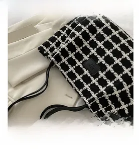 Détail du sac cabas à damier noir et blanc montrant la texture tweed et le logo en cuir
