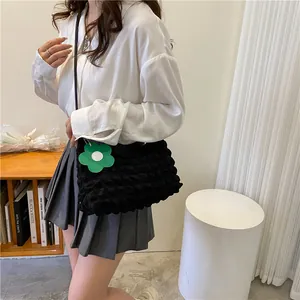 Détail du sac à main noir à texture bulle avec pendentif fleur verte porté