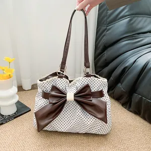 Retro polka dot tote bag with large brown bow and lace trim on a cozy sofa background