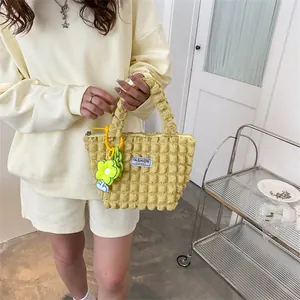 Detail of yellow bubble textured tote bag with metal zipper and sunflower charm