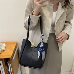 Détail du sac cabas noir minimaliste avec foulard décoratif en soie sur la poignée