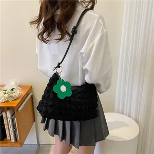 Détail du sac à bandoulière noir en tissu bullé avec pendentif marguerite sur mannequin