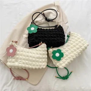 Détail de sacs bandoulière texturés à bulles avec breloques fleurs et poignées nouées