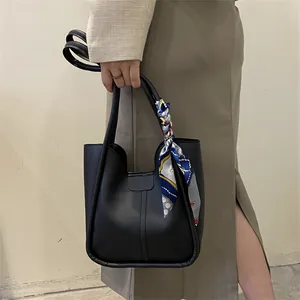 Détail du sac cabas en cuir noir avec foulard en soie imprimé sur l'anse et coutures fines
