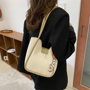 Gros plan d'un sac cabas crème minimaliste avec foulard en soie et finitions kaki