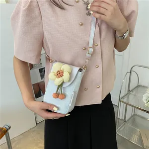 Mini white crossbody phone bag featuring a fabric flower and orange cherry pendants