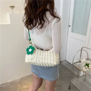 Sac bandoulière blanc à texture bulles avec sangle verte et breloque fleurie sur modèle