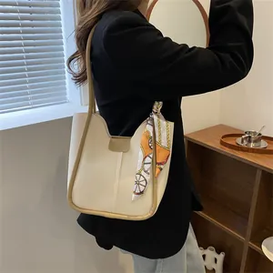 Détail du sac cabas crème avec bordure marron et foulard décoratif en soie sur l'anse