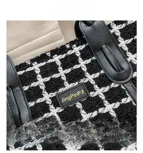 Vue détaillée de la texture du tweed à carreaux et de l'étiquette en cuir avec logo doré