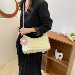 Sac à bandoulière blanc crème à texture popcorn avec breloque fleur rose porté