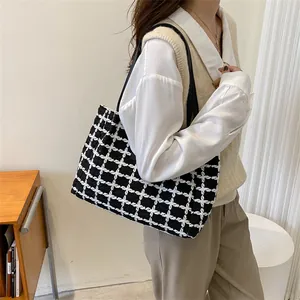 Détail d'un sac cabas en tweed à carreaux noir et blanc sur l'épaule d'un modèle