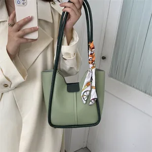 Détail du sac seau vert clair avec bordure foncée et foulard en soie décoratif