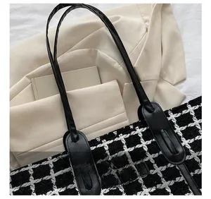 Détail d'un sac cabas en tweed à carreaux noir et blanc avec bandoulière en cuir renforcé