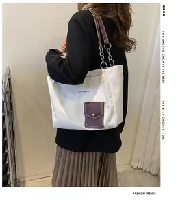 Macro detail of the white canvas tote bag with brown leather accents and chain straps