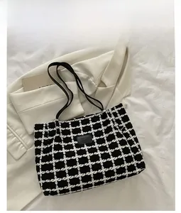 Détail d'un cabas à carreaux noir et blanc avec écusson en cuir sur tweed texturé