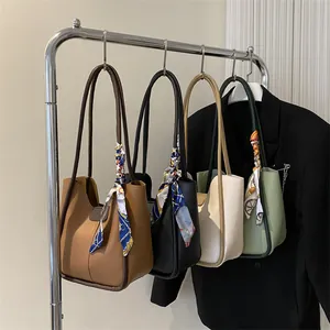Détail de grands sacs seau en similicuir en quatre couleurs avec foulards en soie aux anses