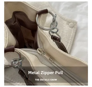 Detail of silver metal zipper pull and chain link on a beige canvas tote bag
