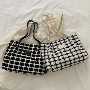 Détail du sac cabas tissé à carreaux montrant la texture épaisse et le patch cuir