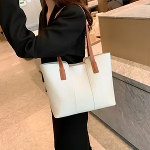 Détail d'un sac cabas en cuir blanc avec des bretelles marron porté à l'épaule