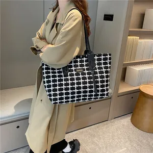 Détail du cabas en tweed à carreaux avec poignées en cuir noir et logo doré en métal