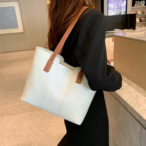 Détails du sac cabas blanc avec coutures verticales et bandoulières en cuir marron