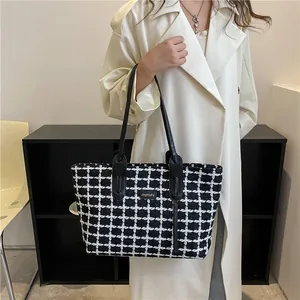 Gros plan du sac cabas en tweed à carreaux noir et blanc avec logo doré et cuir noir