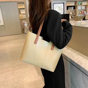 Vue détaillée d'un grand sac cabas en cuir beige porté par un mannequin dans une librairie