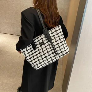 Détail du sac cabas à motif pied-de-poule noir et blanc avec étiquette logo et fine bandoulière