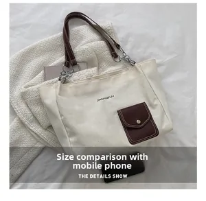 Size comparison of white canvas tote bag with a smartphone and brown leather strap