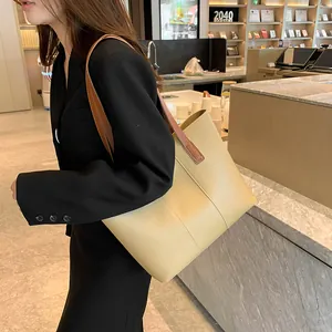 Grand sac cabas beige minimaliste avec anses en cuir marron présenté dans une librairie moderne