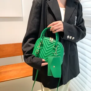 Grüne Muschel-Handtasche mit V-Steppmuster und passendem Mini-Münzbeutel-Detail