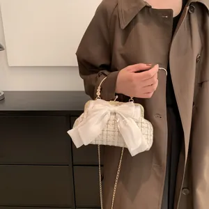 Detail of beige tweed bag with organza bow, metal handle and delicate chain strap