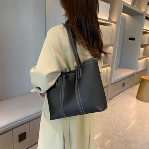Détail d'un grand sac fourre-tout noir avec surpiqûres blanches et longues bretelles