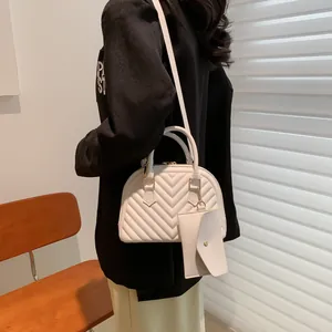 Detailansicht einer weißen gesteppten Handtasche mit kleiner Münztasche und Schultergurt