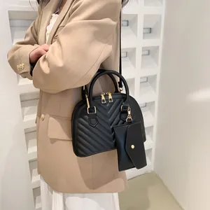 Detail der schwarzen gesteppten Muscheltasche mit goldener Hardware und Mini-Anhänger