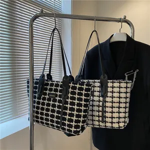 Gros plan de sacs cabas en tweed à carreaux noir et blanc suspendus sur un cintre