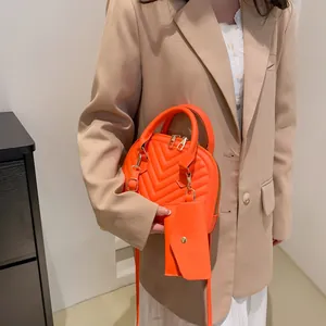 Detail der leuchtend orangefarbenen Muscheltasche mit V-Steppung und passender Münztasche