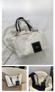 Detail of off-white canvas tote bag with black pocket and leather chain shoulder strap