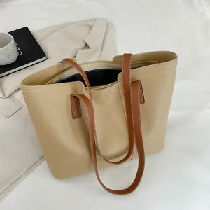 Détail d'un grand sac cabas beige avec bandoulières brunes et surpiqûres blanches