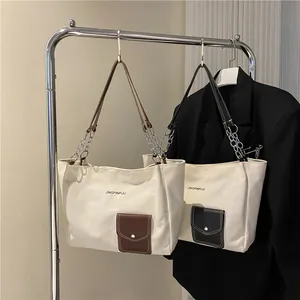 Detail of canvas tote bags with leather pockets and chain straps on a hanger