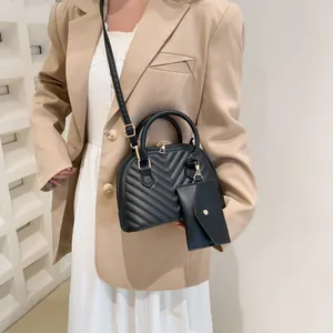 Elegante schwarze Muschel-Umhängetasche mit Chevron-Steppung und passender Geldbörse am Model