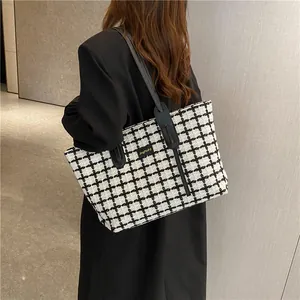 Sac fourre-tout classique à carreaux noir et blanc avec anses en cuir sur un mannequin
