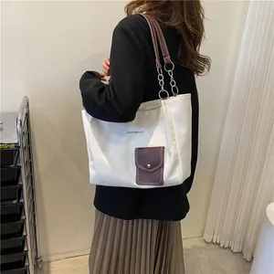 Chic cream canvas tote bag with dark brown leather straps and metal chain detail