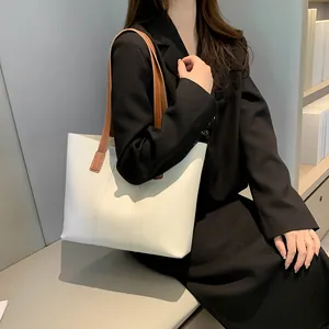 Sac fourre-tout minimaliste en cuir beige avec anses marron porté par un mannequin