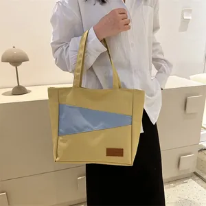 Detail der Canvas-Tragetasche mit Farblock-Design und ledernem FASHION-Etikett sowie Naht