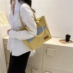 Detailansicht der gelb-hellblauen Canvas-Tasche, getragen von einem Modell im Raum
