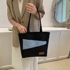 Detailaufnahme der schwarzen Oxford-Stofftasche mit hellblauen Nähten und Fashion-Label